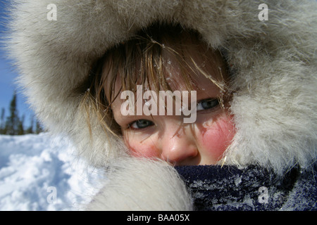 A young blue-eyed, blond-haired girl in a fur jacket in the Arctic community of Old Crow, Yukon Territory. Stock Photo