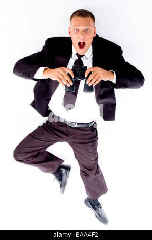 handsome young executive lying on floor holding binoculars Stock Photo