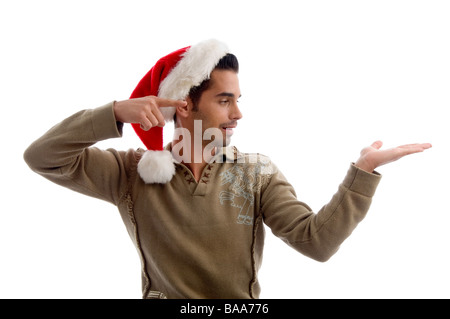 young man wearing christmas hat and indicating to his hand Stock Photo