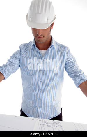 young caucasian architect in helmet having a look at blueprints Stock Photo
