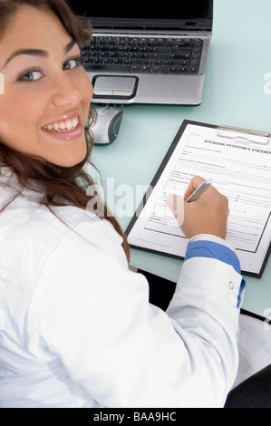 smiling doctor holding pen and looking at camera Stock Photo