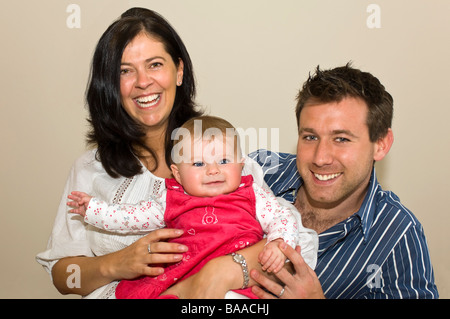 Horizontal close up portrait of proud parents sitting with their cute baby daughter Stock Photo