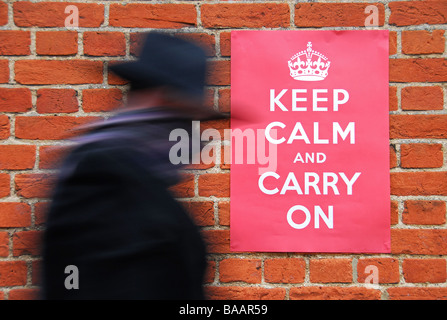 Man walking past a Second World War poster urging people to keep calm and carry on. Stock Photo