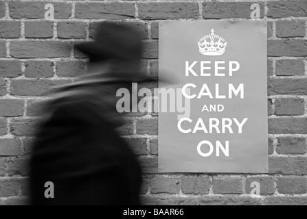 Man walking past a Second World War poster urging people to keep calm and carry on. Stock Photo