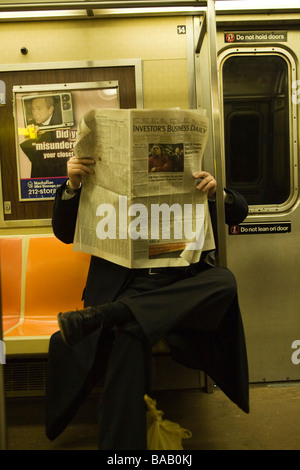 Man reads the Investors Daily Newspaper on a subway train in NYC to keep up on the world financial meltdown Stock Photo