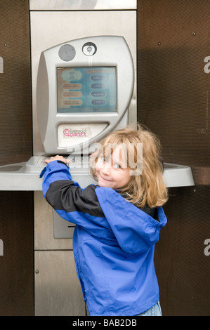 Young girl using public Internet telephone kiosk. FULLY MODEL RELEASED Stock Photo