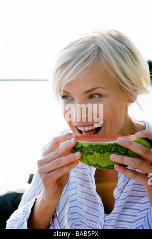 A woman eating a watermelon by the sea in the archipelago of Stockholm, Sweden. Stock Photo