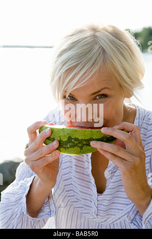 A woman eating a watermelon by the sea in the archipelago of Stockholm, Sweden. Stock Photo