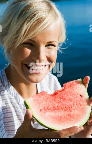 A woman eating a watermelon by the sea in the archipelago of Stockholm, Sweden. Stock Photo