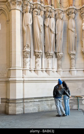 Visitors admiring sculptures on the facade of the Cathedral of St. John the Divine in New York CIty Stock Photo