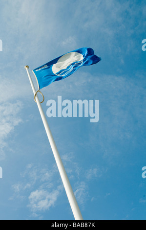 A Blue Flag flying against a blue sky with some cloud cover on the beach at  Brighton, england Stock Photo