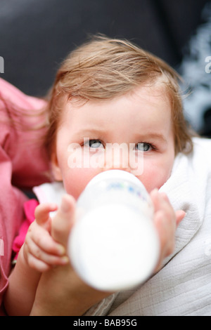 A ten month old baby girl is bottle fed by her mother Stock Photo