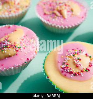 Home made cup cakes decorated with pink and yellow icing and hundreds n thousands. Also called fairy cakes. Stock Photo