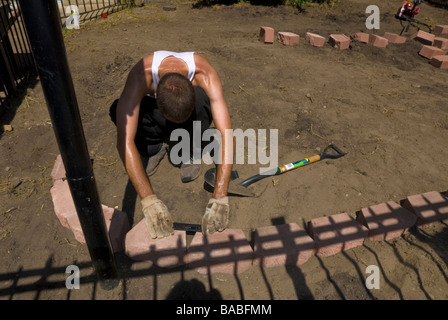 Italian landscaping construction worker laying pavers for raised flower garden for an apartment building in Chicago Illinois Stock Photo