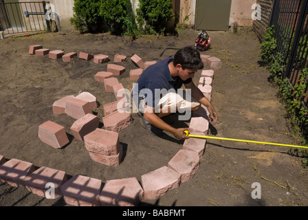 Hispanic Italian landscaping architect laying pavers for raised flower garden for an apartment building in Chicago Illinois Stock Photo
