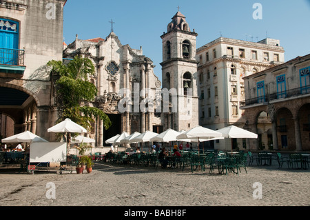 Cathedral Square in Old Havana with arched columns, a church with bell tower and a cafe in the foreground. Stock Photo