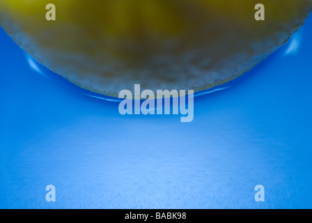 Lemon floating in blue water background, close-up Stock Photo
