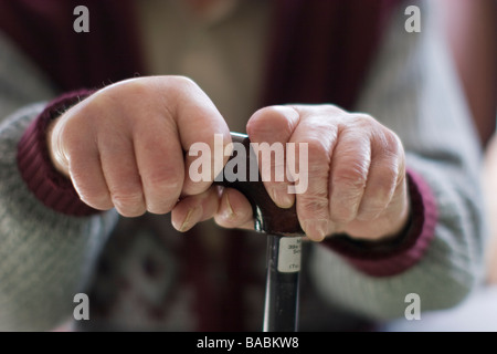 elderly man oap old age pensioner hands clutching walking stick while sitting at home Stock Photo