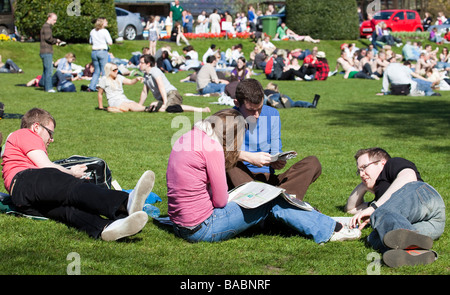 People enjoying a bright spring day on a lawn in Glasgow's Botanic Gardens. Stock Photo