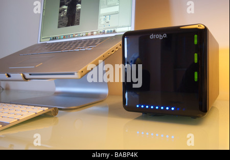 2009 Drobo brand RAID hard disc unit seen with Apple Macbook laptop computer in home office environment Stock Photo