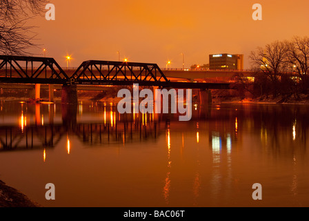 A railroad bridge spans the calm Wabash River outside of Lafayette, Indiana, on a cold winter night. Stock Photo