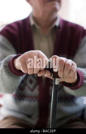 elderly man oap old age pensioner hands clutching walking stick at home Stock Photo