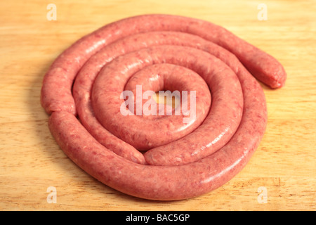 A coil of raw boerewors sausauge a South African favourite ready for grilling on a wooden board Stock Photo