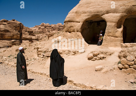 A Muslim family wandering in the rock cut tombs at the entrance to the ancient Nabatean city of Petra Jordan Stock Photo