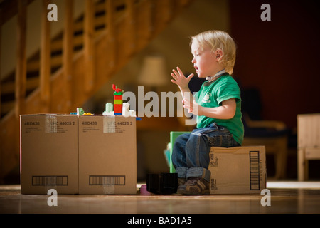 Toddler saying Mom using sign language while playing with toys on cardboard boxes Stock Photo