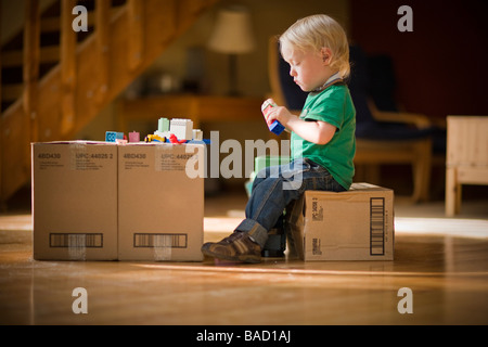 Toddler playing with toys on cardboard boxes Stock Photo