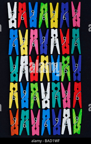 Coloured small clothes pegs pattern on a black background Stock Photo