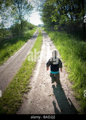 Toddler walking along a gravel road Stock Photo