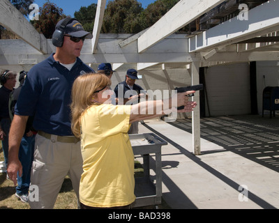 Police officer instructs female citizen police academy member in using the Glock 9mm automatic pistol, on the police range Stock Photo