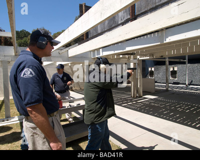 Citizen police academy member fires Glock 9mm automatic pistol as range officer looks on Stock Photo