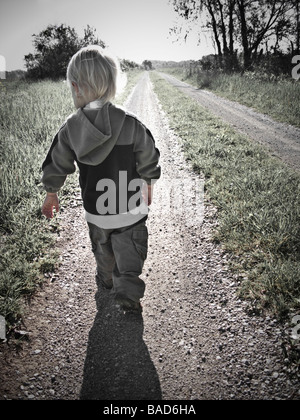 Toddler walking along a gravel road Stock Photo