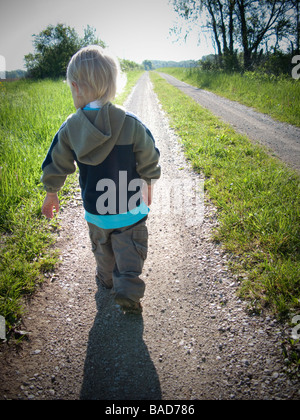 Toddler walking along a gravel road Stock Photo