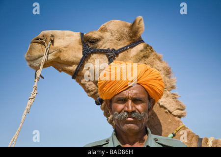 Man standing beside a camel at Osian Camel Camp, Osian, Rajasthan, India Stock Photo