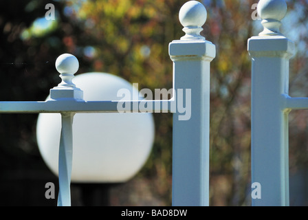 Metal fence and gate posts with out of focus top of lightpost in background Stock Photo