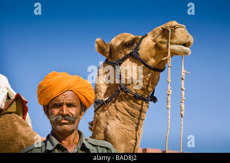 Man standing beside a camel at Osian Camel Camp, Osian, Rajasthan, India Stock Photo