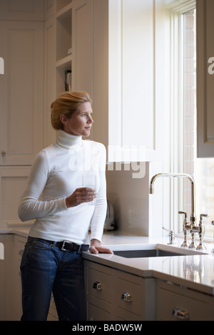Woman Filling Glass from Kitchen Faucet Stock Photo