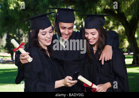 College Graduates Looking at Cellular Phone Stock Photo