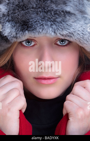 Close up of a woman wearing a fur hat and red coat with the collars pulled up Stock Photo
