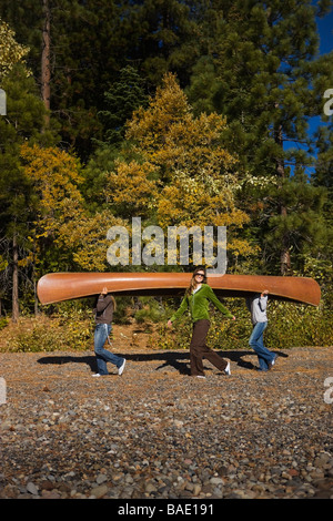 Three Women Carrying Canoe in the Forest Stock Photo