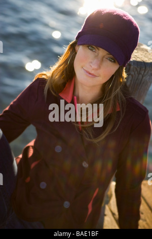 Woman Sitting On Dock by Lake Stock Photo