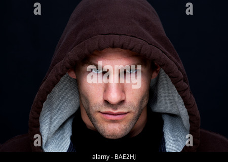 Headshot of a man wearing a brown hooded top with an intense stare Stock Photo