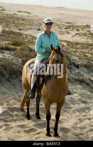 MEXICO Todos Santos Woman riding horse with western saddle on the beach along Pacific Ocean Playa La Cachora Stock Photo
