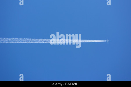 A jet passenger aircraft flying at high altitude with Contrails visible against a clear blue sky. Stock Photo