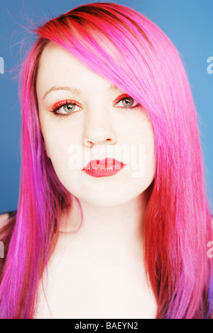 Young teen with bright pink hair and red lips looking straight at camera Stock Photo