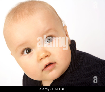 A baby looks startled against a white background Stock Photo