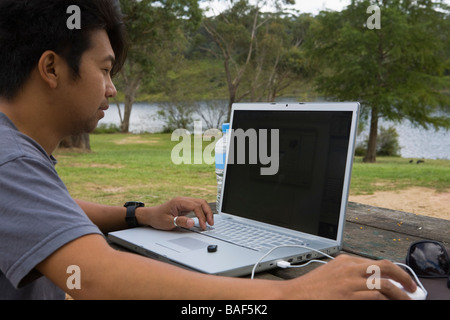 Young man working with laptop on park table outdoors Stock Photo